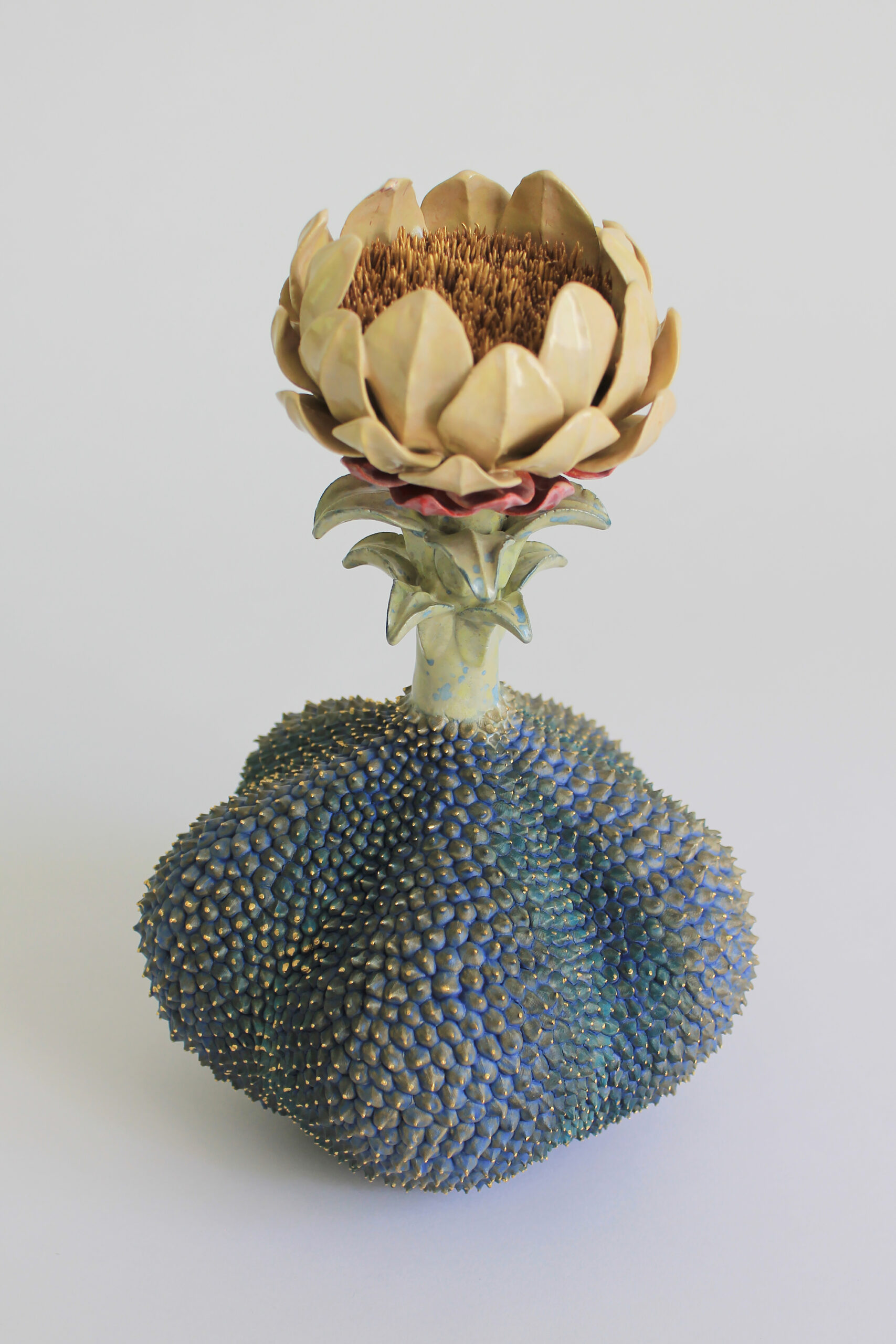 An abstract sculpture of an imaginary plant made from ceramic with a large yellow flower on top.