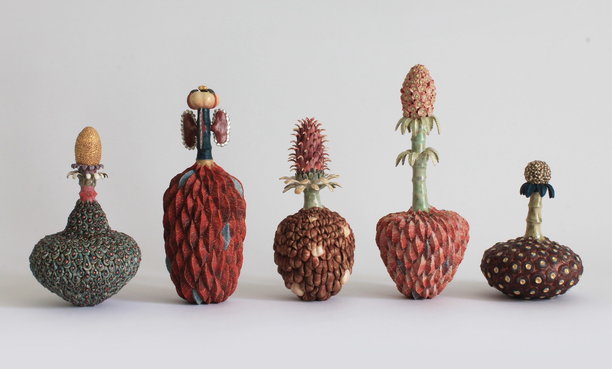 An display of five ceramic sculptures inspired by plants and flowers.