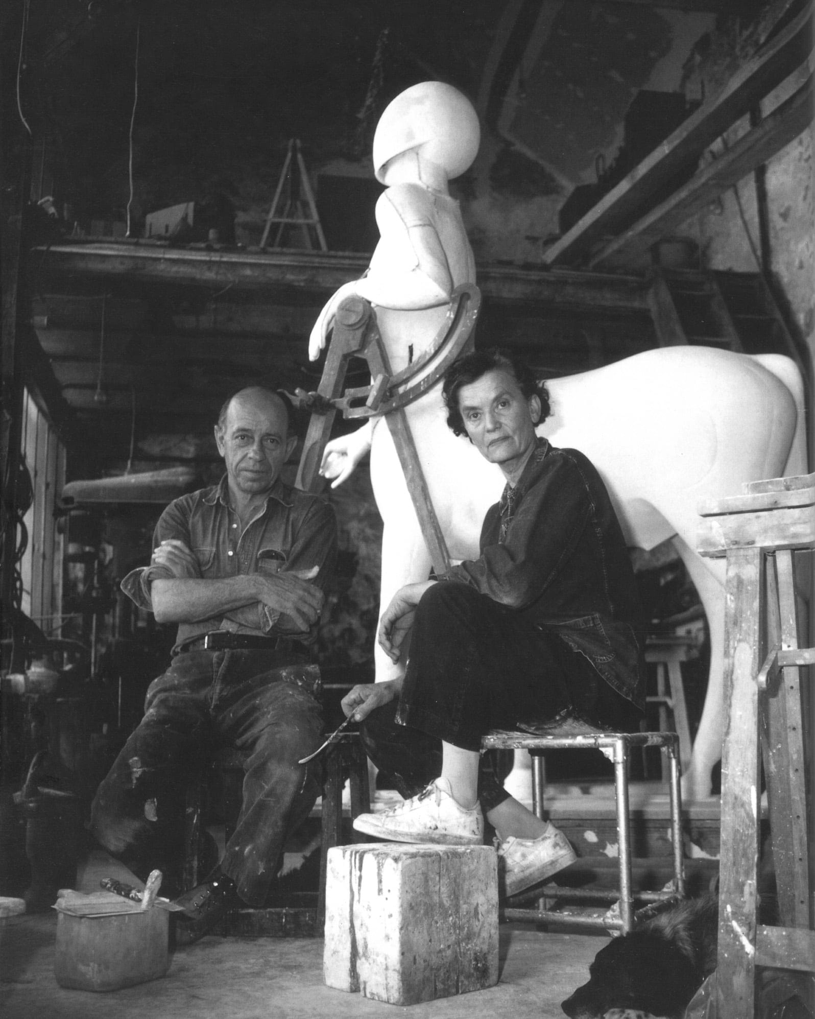 a black and white photo of the artists seated in front of the centaur sculpture