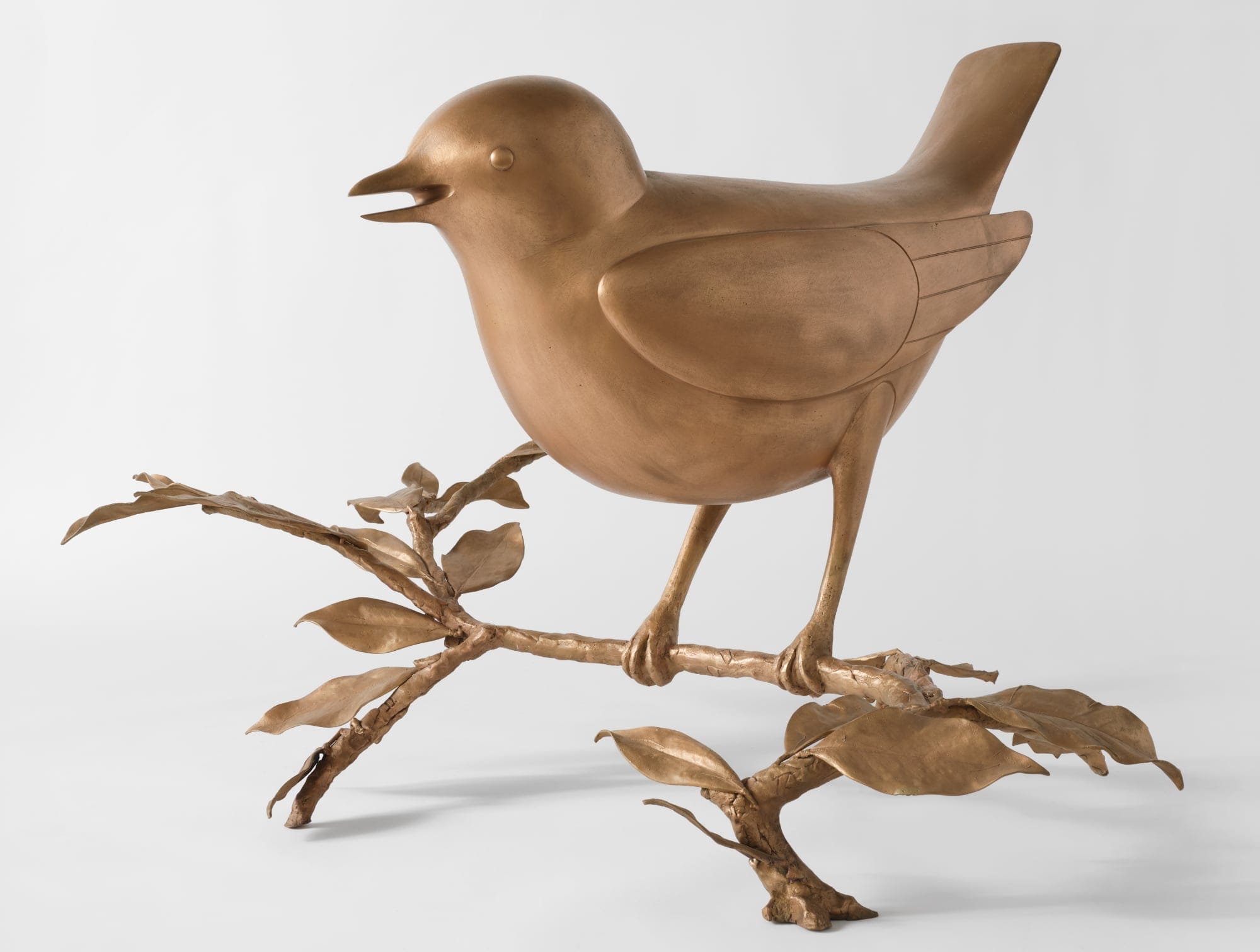 a bronze bird resting on a twig
