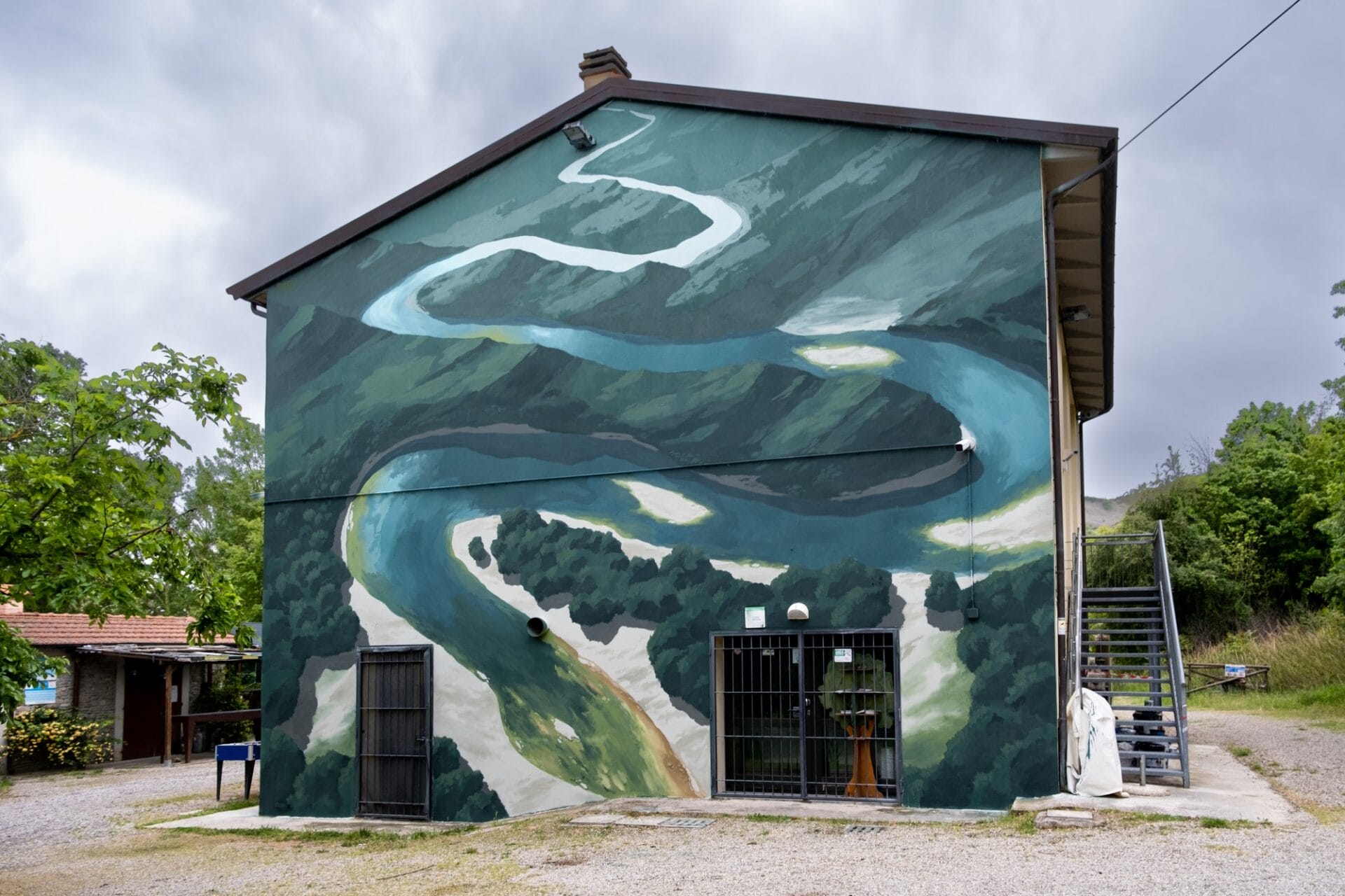 a mural on the side of a building showing a river coursing through some mountains